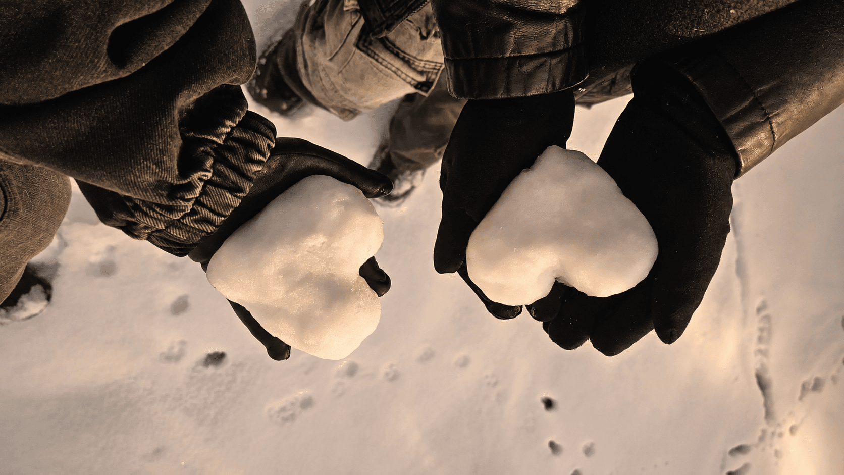 Two snow hearts held in gloved hands