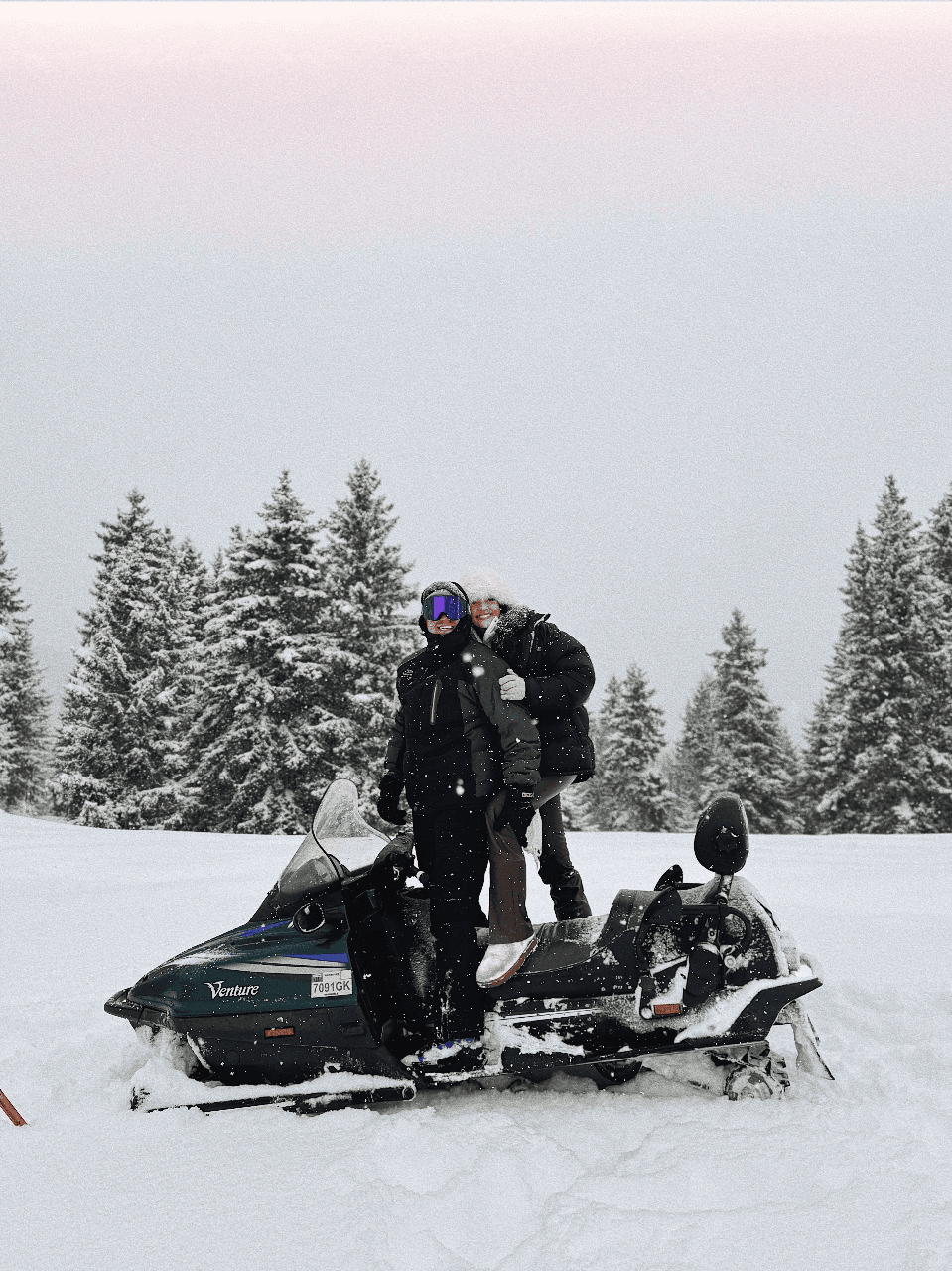 Couple riding a snowmobile in the snowy mountains