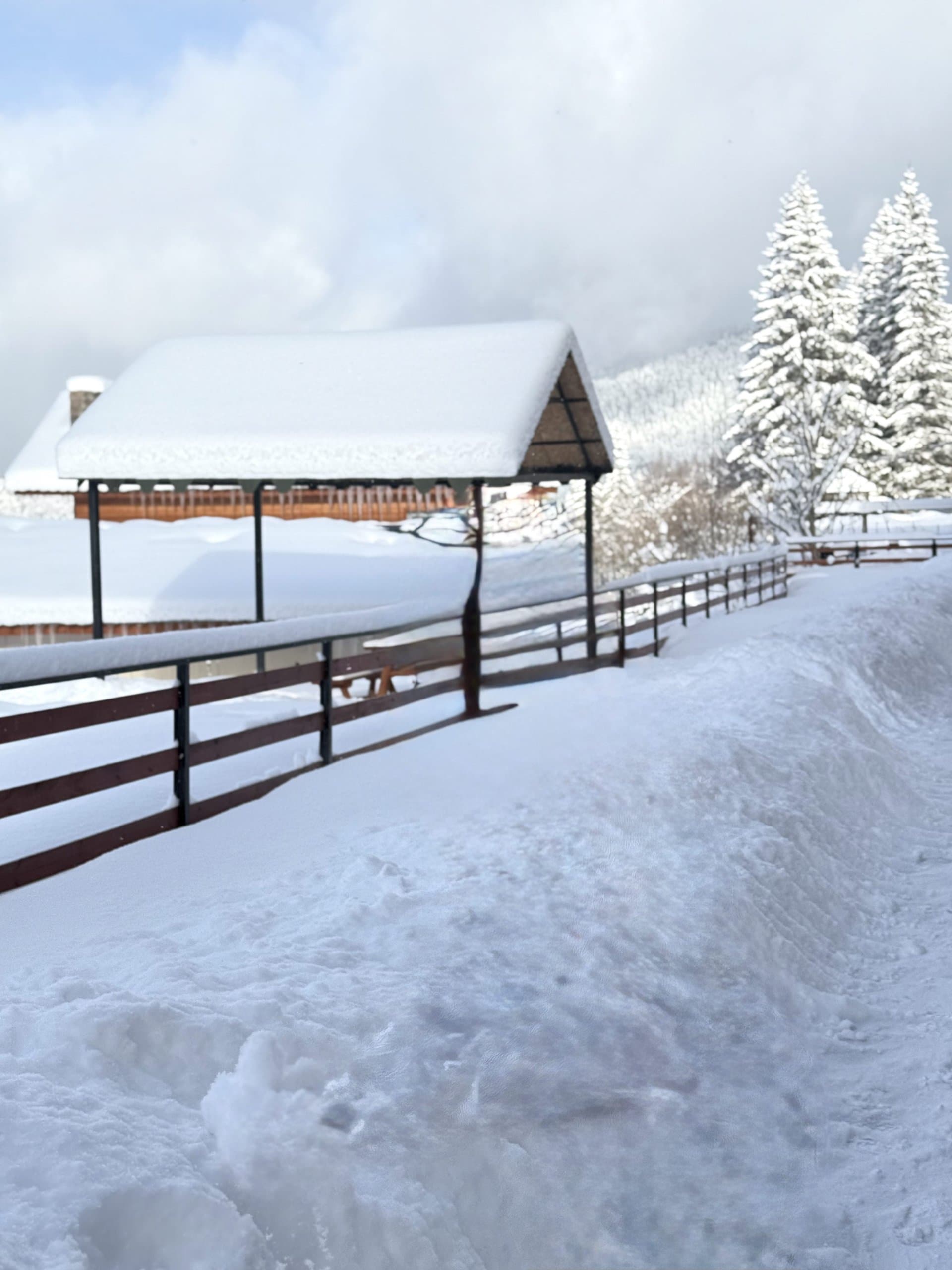 Snow-covered outdoor area beside mountain accommodation.