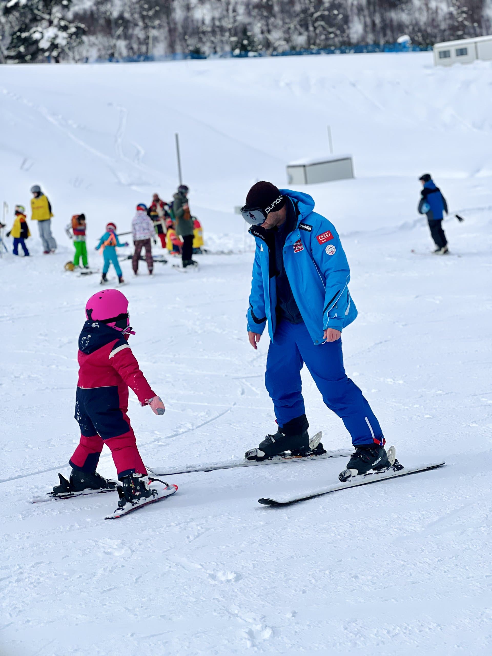 Child skier practising with an instructor on a beginner slope.