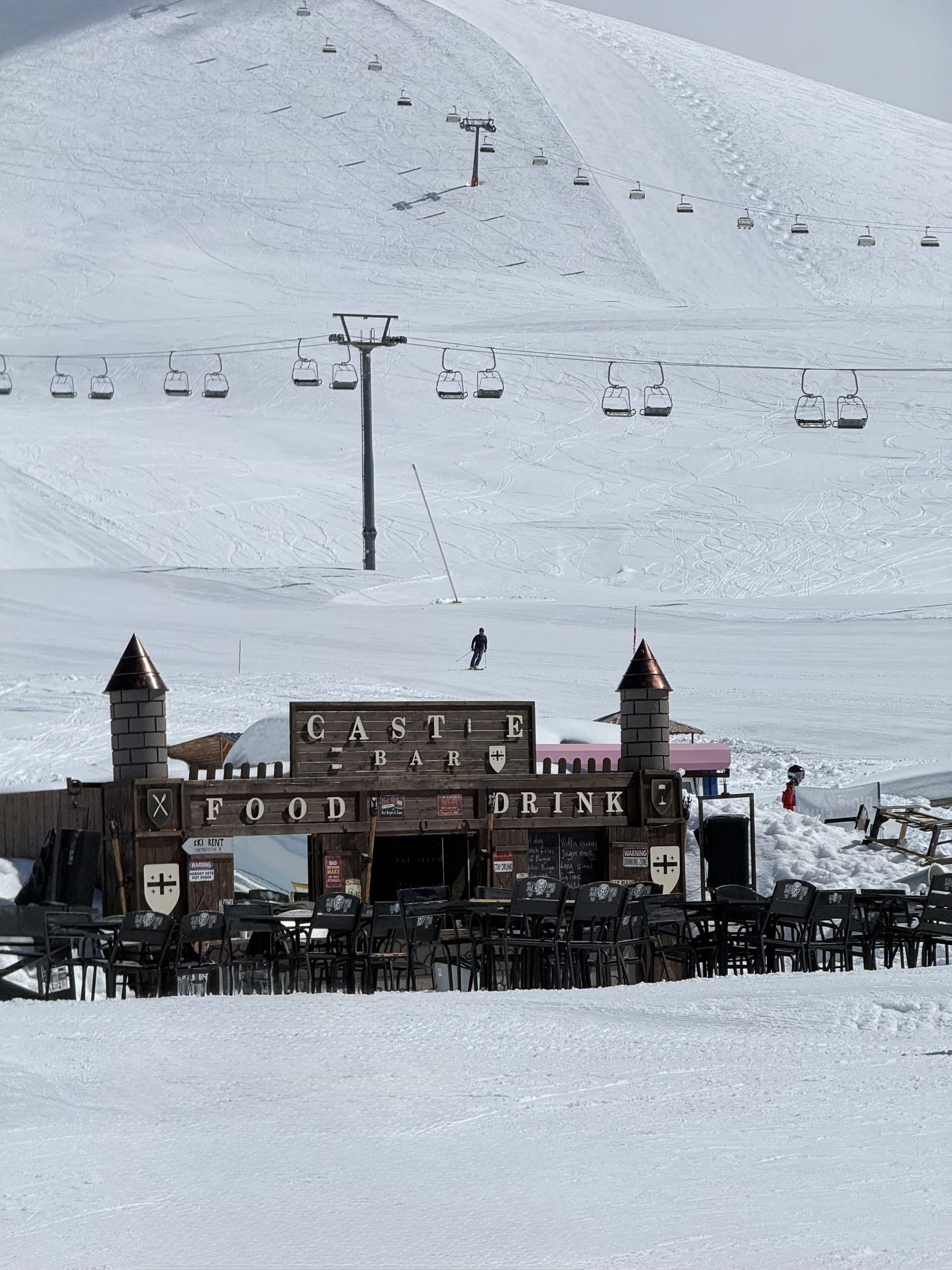 Ski resort base area below snowy mountain slopes.