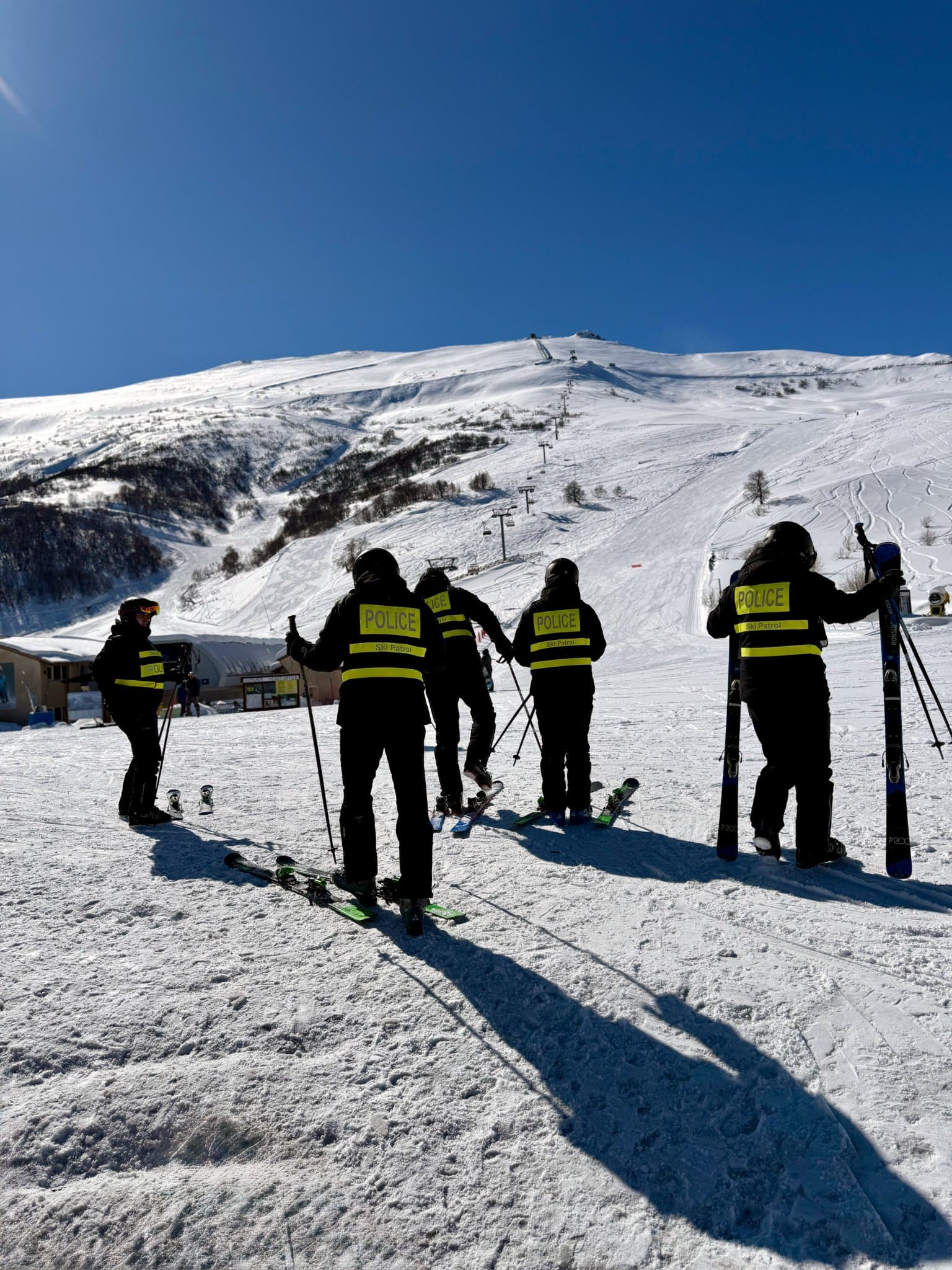 Group of skiers standing on a sunlit snowy ridge.