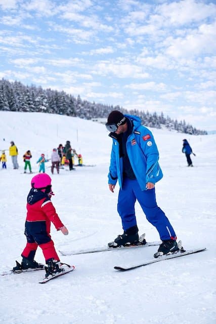Young skier learning with an instructor on a beginner slope.