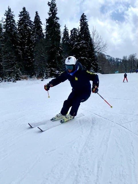Skier descending a groomed snowy slope.