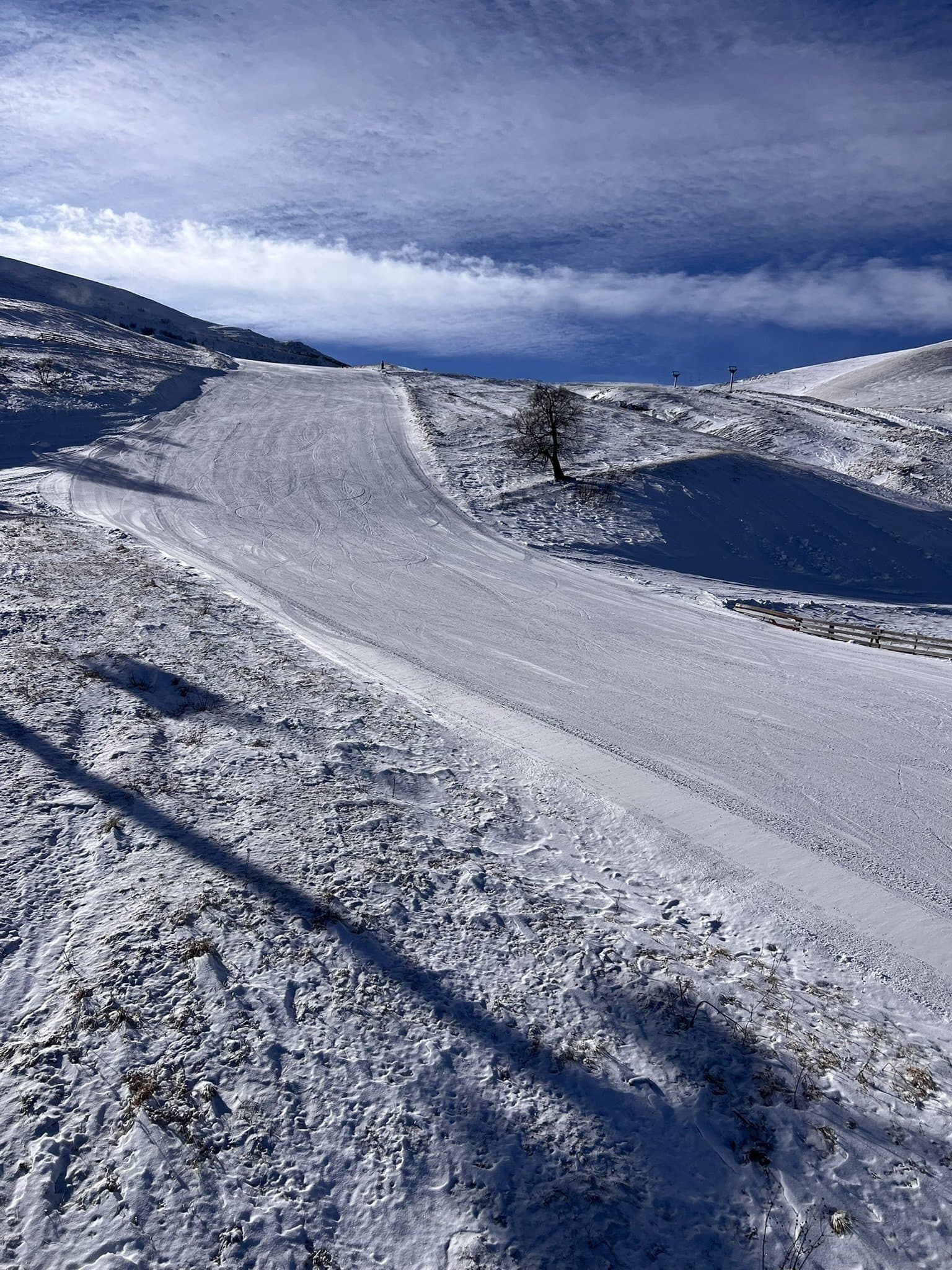 Ski tracks across a wide snow-covered mountain slope.
