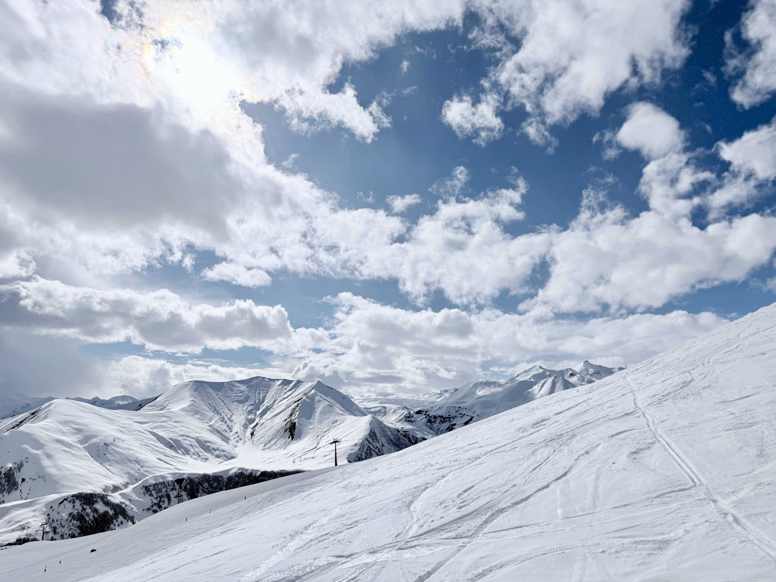 Wide snow-covered mountain panorama beneath winter clouds.
