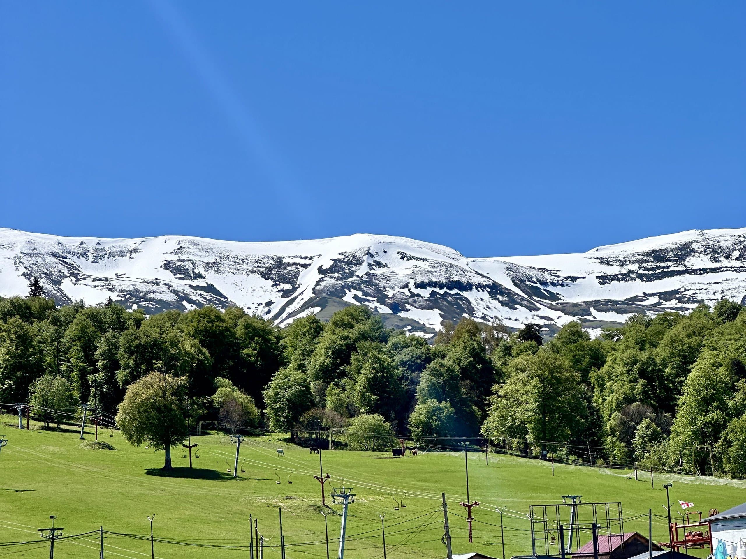 Green mountain slopes with patches of snow in summer.