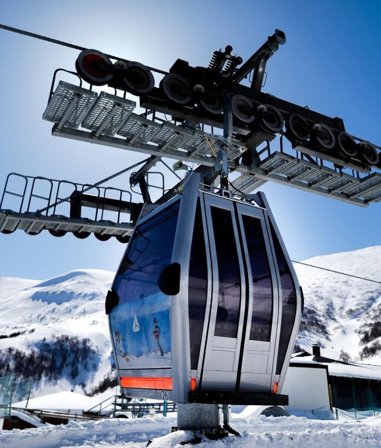 Gondola lift above a snowy Georgian ski resort.