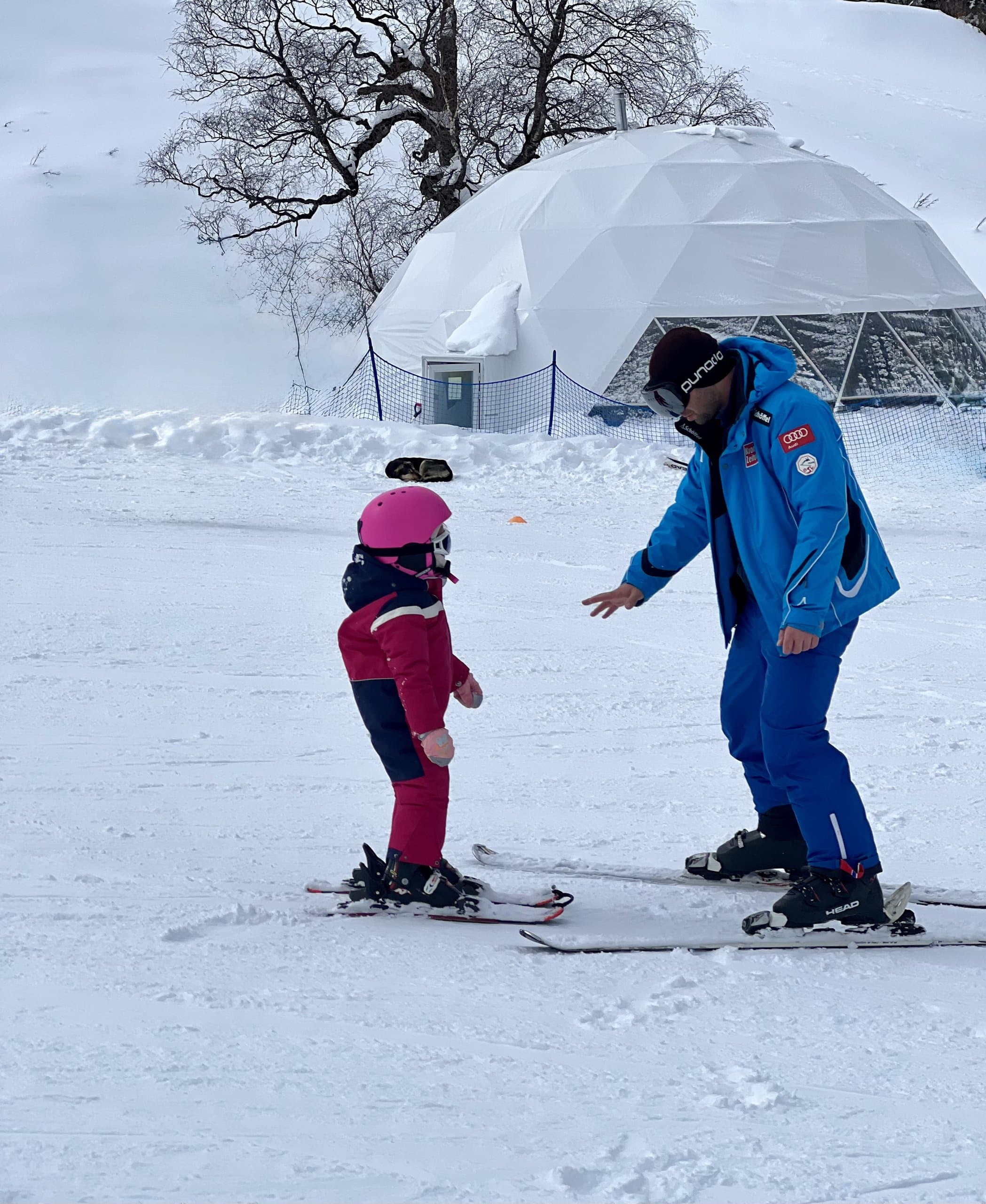 A young skier receives a lesson on a beginner slope.