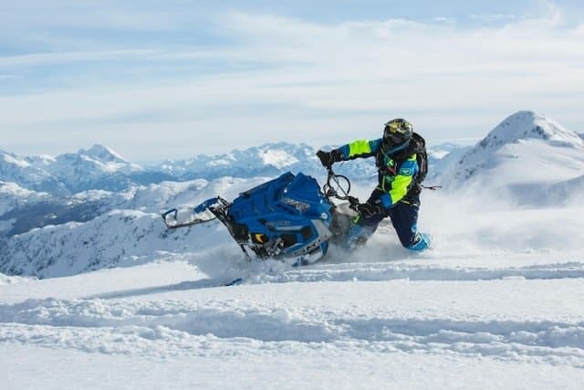 Snowmobile rider travelling through deep mountain snow.
